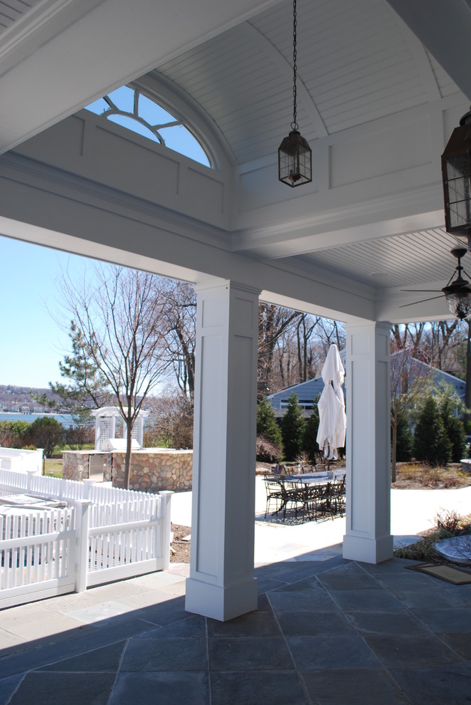 Example of a large beach style stone patio design in New York with a roof extension