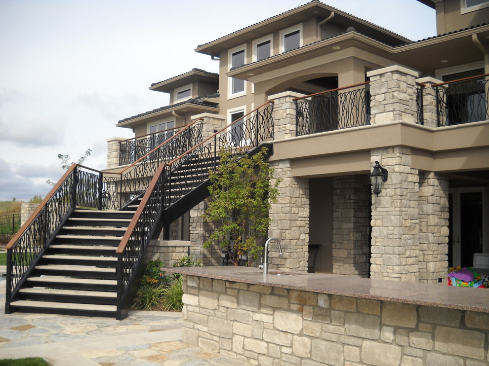 Photo of a large traditional back patio in Other with an outdoor kitchen and natural stone paving.