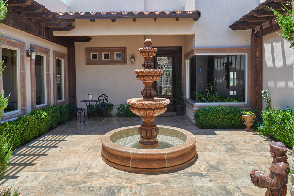 Diseño de patio mediterráneo en patio con fuente, suelo de baldosas y pérgola