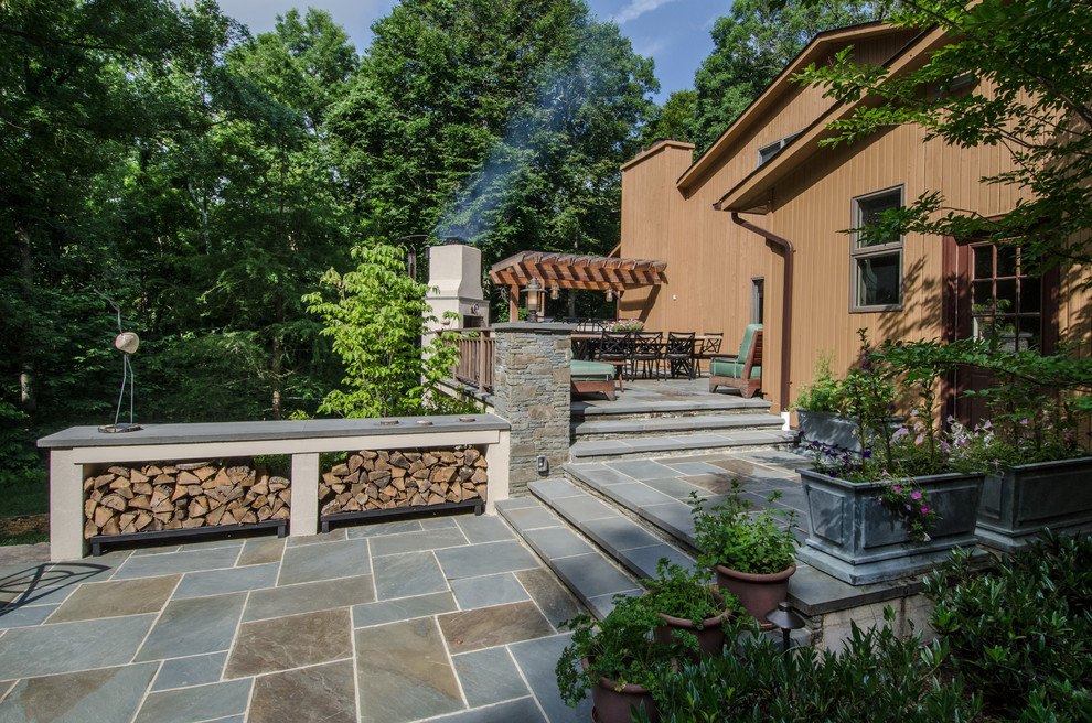 Foto di un ampio patio o portico stile americano dietro casa con un focolare, pavimentazioni in pietra naturale e una pergola