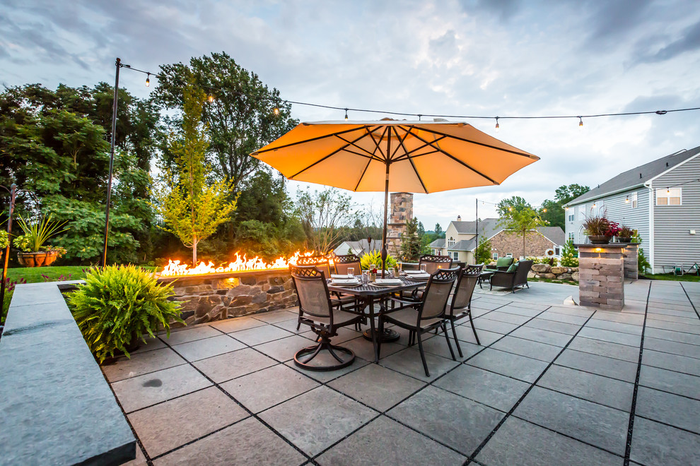 Large arts and crafts backyard stone patio photo in Philadelphia with a fire pit and no cover