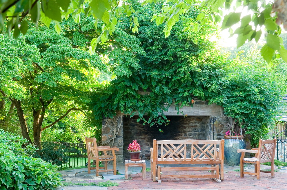 Imagen de patio clásico grande en patio trasero con adoquines de ladrillo y chimenea
