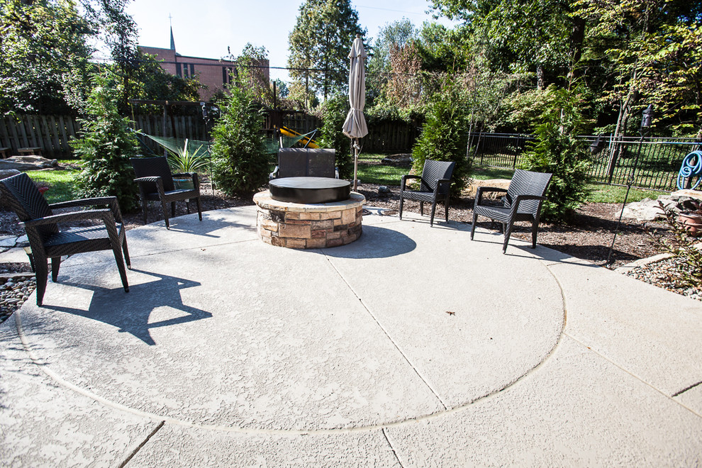 Modelo de patio de estilo americano de tamaño medio en patio trasero con brasero y suelo de hormigón estampado