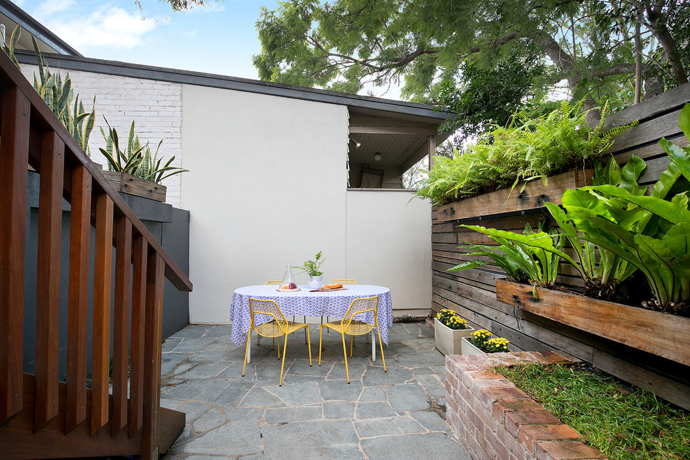 Foto de patio actual sin cubierta en patio trasero con jardín de macetas y adoquines de piedra natural