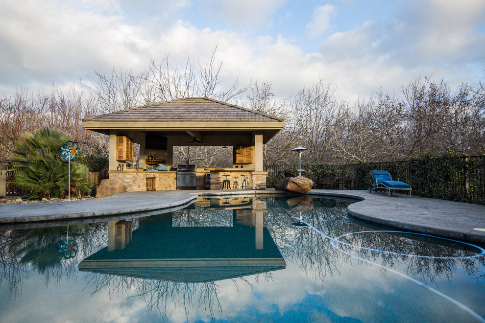 Cette image montre une grande terrasse arrière minimaliste avec une cuisine d'été, un gazebo ou pavillon et du béton estampé.