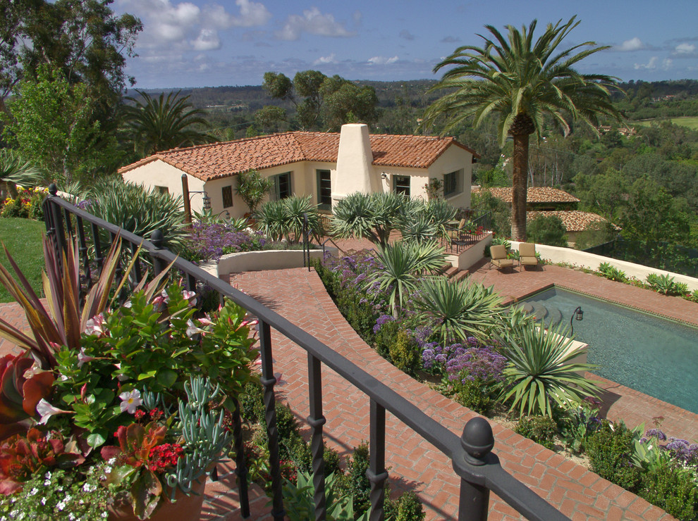 Réalisation d'une terrasse avec des plantes en pots arrière méditerranéenne de taille moyenne avec des pavés en brique et aucune couverture.