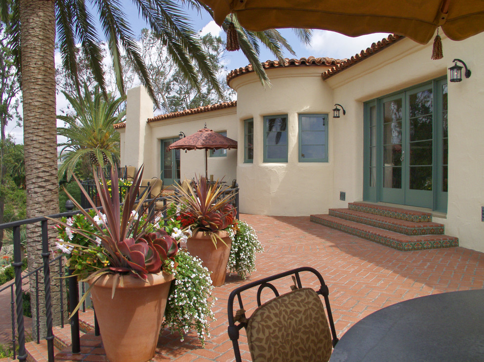 Medium sized mediterranean back patio in San Diego with a potted garden, brick paving and no cover.
