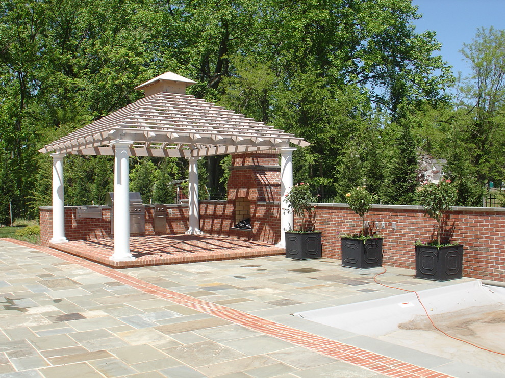 Esempio di un patio o portico classico con un focolare, pavimentazioni in pietra naturale e una pergola