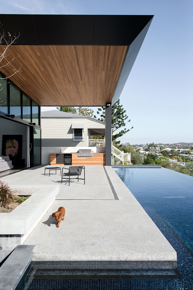 Foto di un grande patio o portico minimal dietro casa con lastre di cemento e un tetto a sbalzo