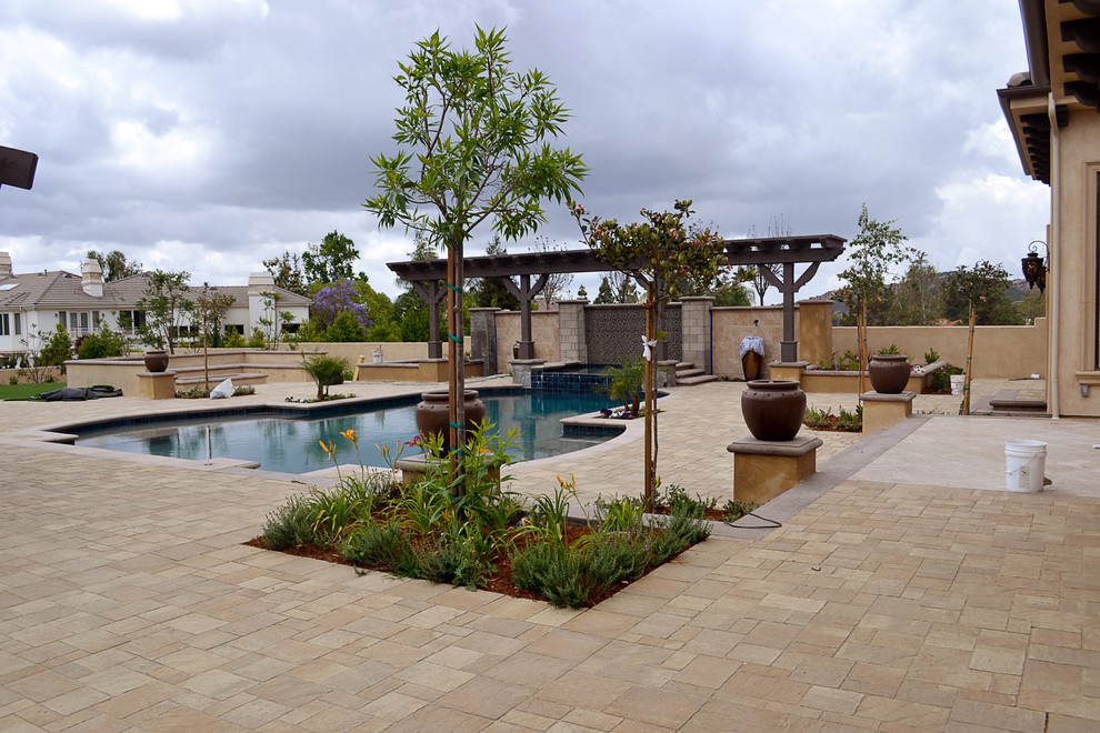 Diseño de patio mediterráneo grande en patio trasero con fuente, adoquines de hormigón y pérgola