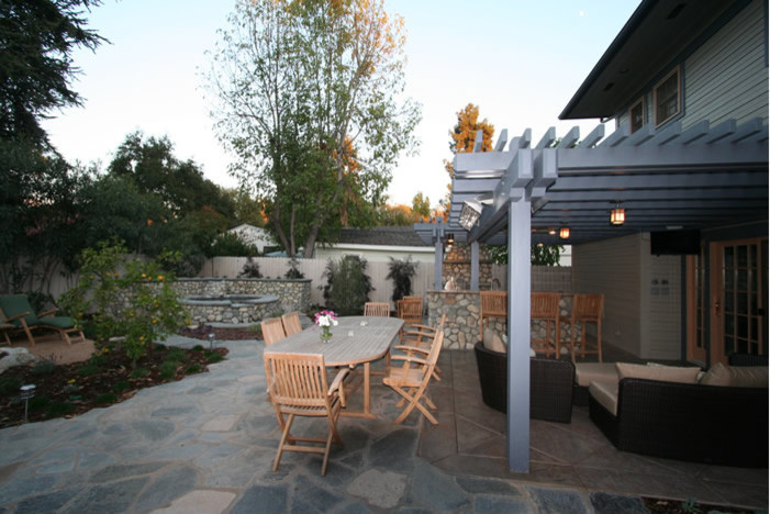 Traditional back patio in Los Angeles with an outdoor kitchen, natural stone paving and a pergola.