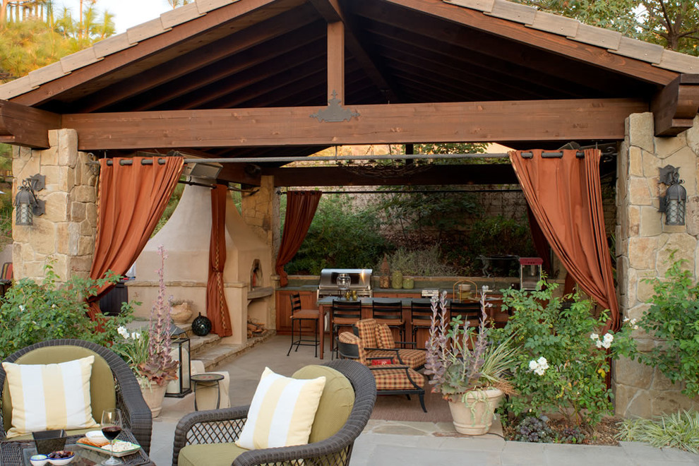 Immagine di un grande patio o portico mediterraneo dietro casa con pavimentazioni in pietra naturale e un gazebo o capanno