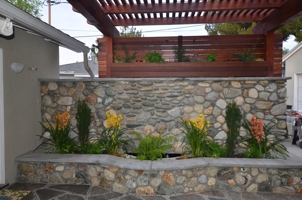Foto di un piccolo patio o portico etnico dietro casa con un focolare, pavimentazioni in pietra naturale e una pergola