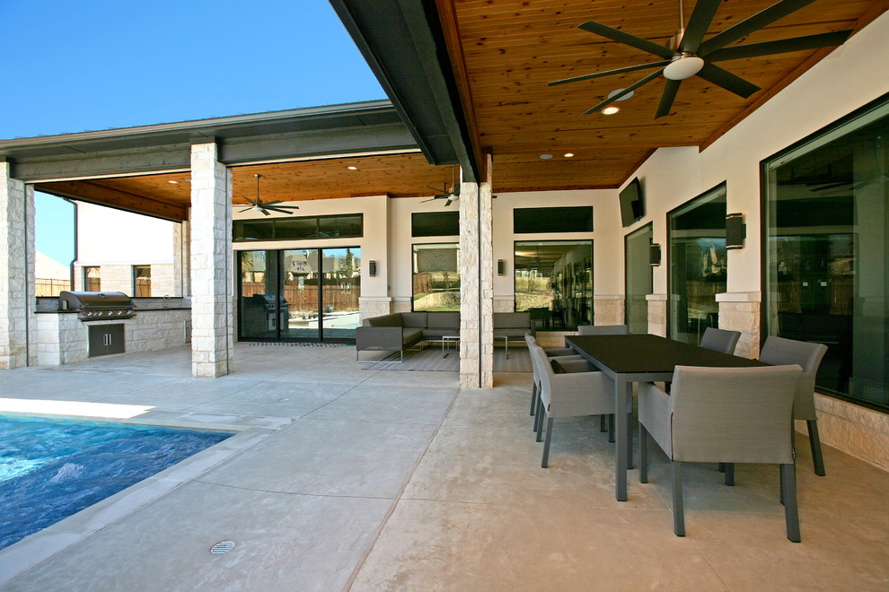 На фото: большой двор на заднем дворе в современном стиле с летней кухней, покрытием из бетонных плит и навесом с