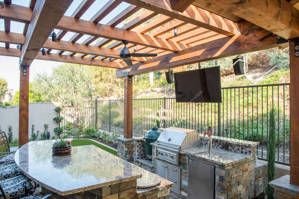 Imagen de patio tradicional renovado de tamaño medio en patio trasero con cocina exterior, adoquines de piedra natural y pérgola
