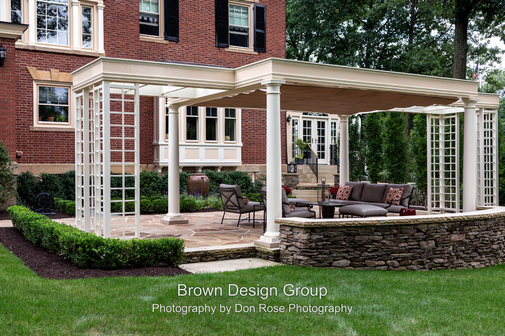 Immagine di un patio o portico classico dietro casa con pavimentazioni in pietra naturale e una pergola