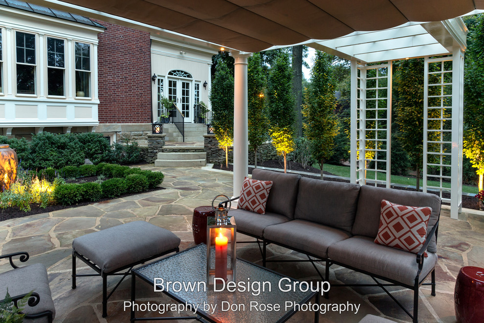 Elegant backyard stone patio photo in Other with a pergola