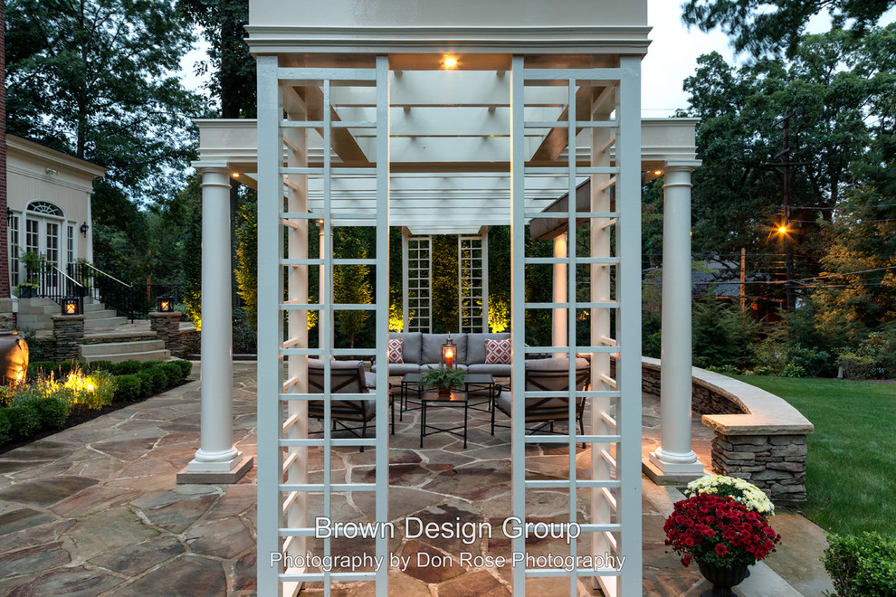 Design ideas for a traditional back patio in Other with natural stone paving and a pergola.