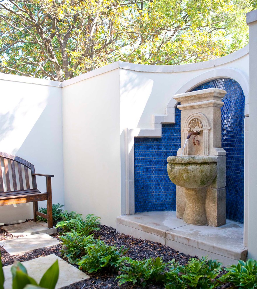 На фото: двор на внутреннем дворе в средиземноморском стиле с фонтаном и покрытием из каменной брусчатки без защиты от солнца с