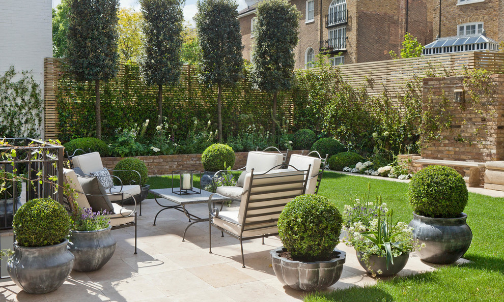 Réalisation d'une terrasse avec des plantes en pots arrière tradition avec des pavés en pierre naturelle et aucune couverture.