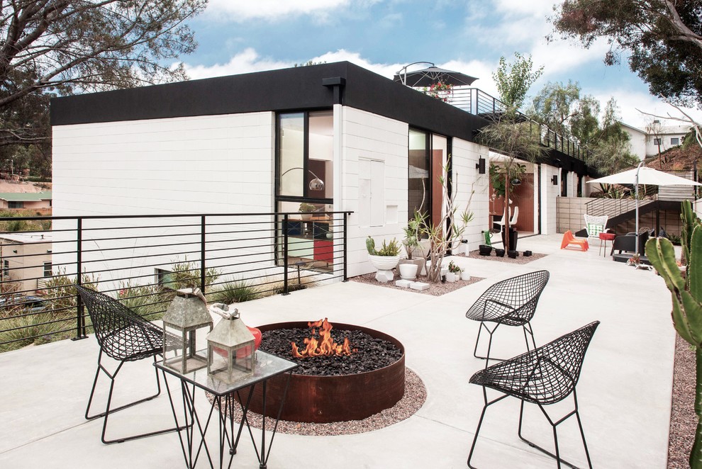 Immagine di un patio o portico minimal dietro casa con un focolare, lastre di cemento e nessuna copertura