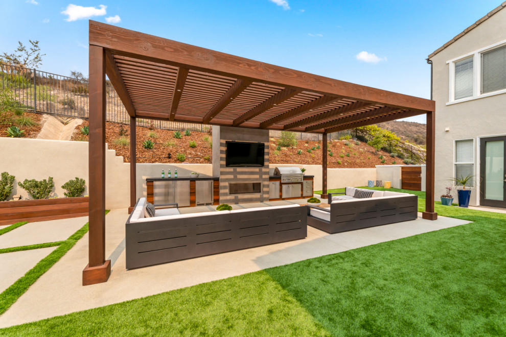 Exemple d'une grande terrasse arrière tendance avec une cuisine d'été, des pavés en béton et une pergola.
