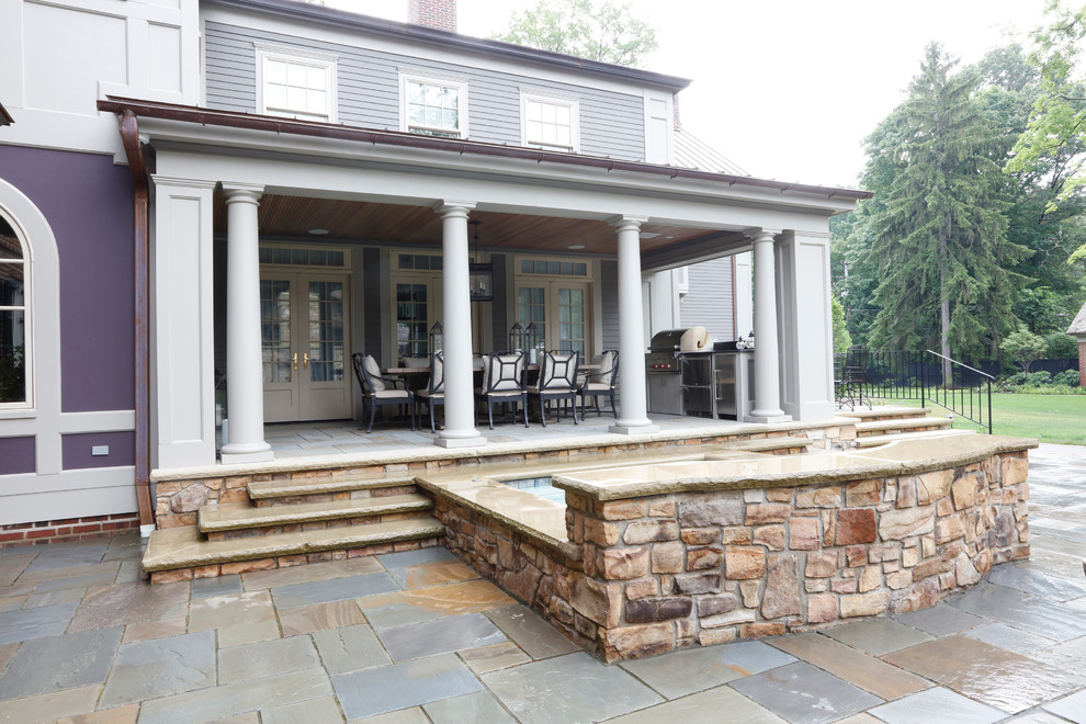 Idée de décoration pour une terrasse arrière tradition de taille moyenne avec une cuisine d'été, des pavés en pierre naturelle et une extension de toiture.