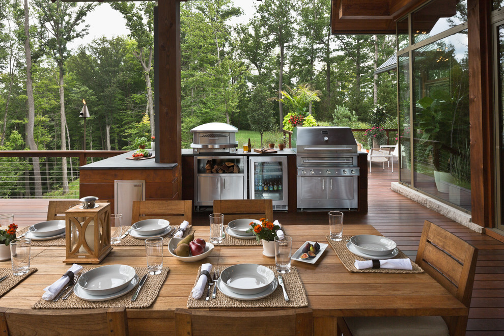 Cette image montre une terrasse en bois design avec une cuisine d'été et une pergola.