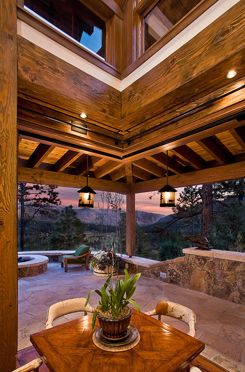 Ispirazione per un grande patio o portico stile rurale dietro casa con pavimentazioni in pietra naturale e un tetto a sbalzo