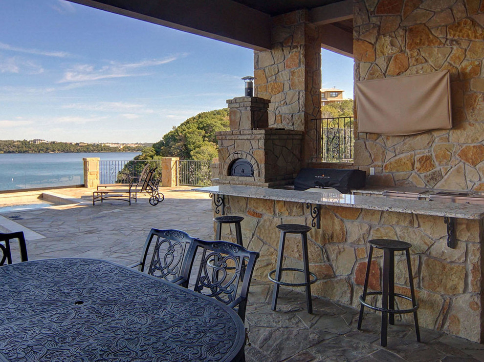Expansive mediterranean back patio in Dallas with an outdoor kitchen, stamped concrete and a roof extension.