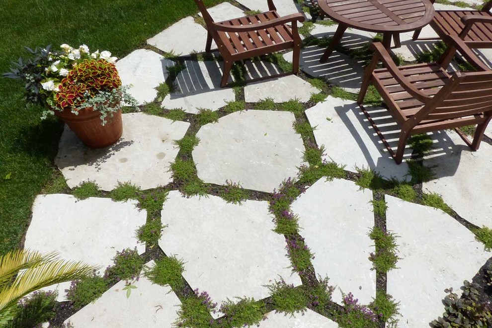 Diseño de patio clásico grande sin cubierta en patio trasero con adoquines de piedra natural