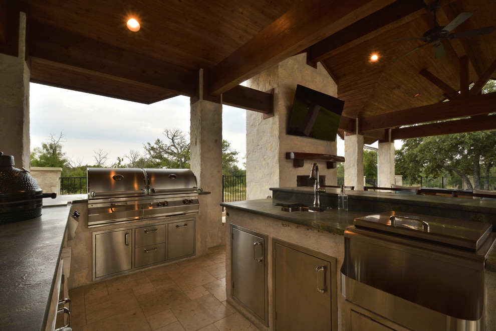 Photo of an expansive traditional back patio in Austin with an outdoor kitchen, natural stone paving and a roof extension.