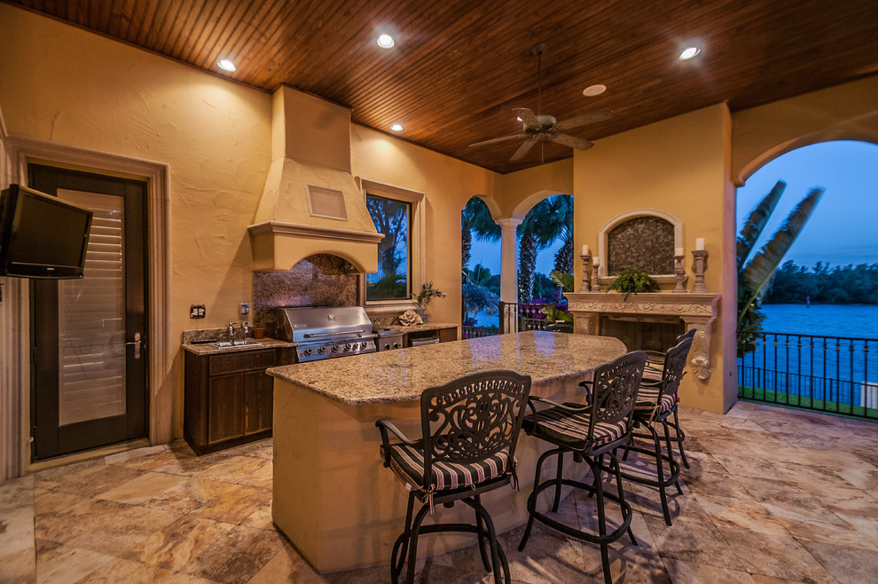 Inspiration for a large mediterranean backyard stone patio kitchen remodel in Tampa