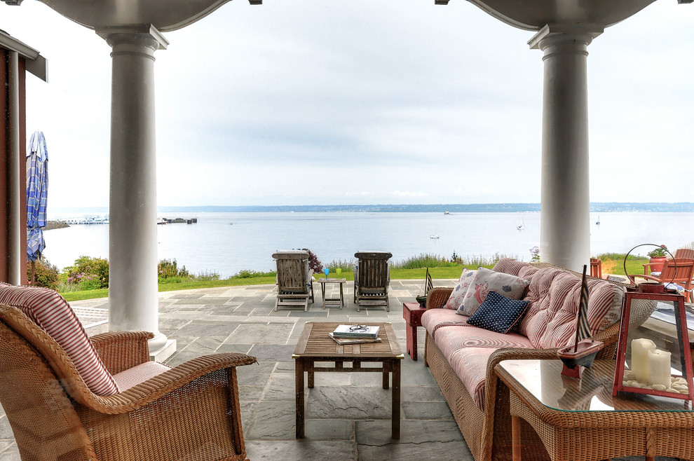 Cette image montre une grande terrasse arrière marine avec des pavés en pierre naturelle et une pergola.