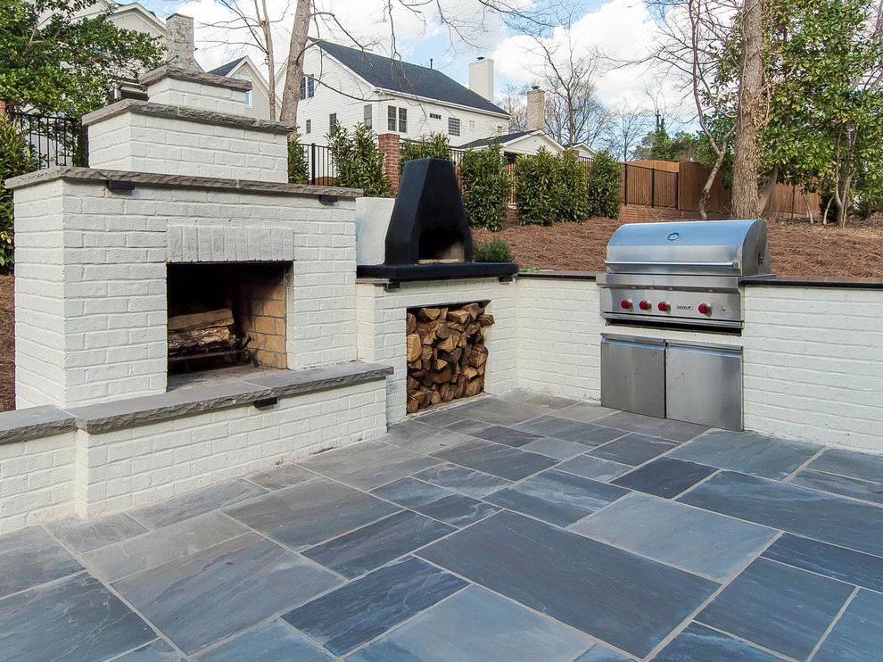 Example of a mid-sized transitional backyard stone patio design in Raleigh with a roof extension
