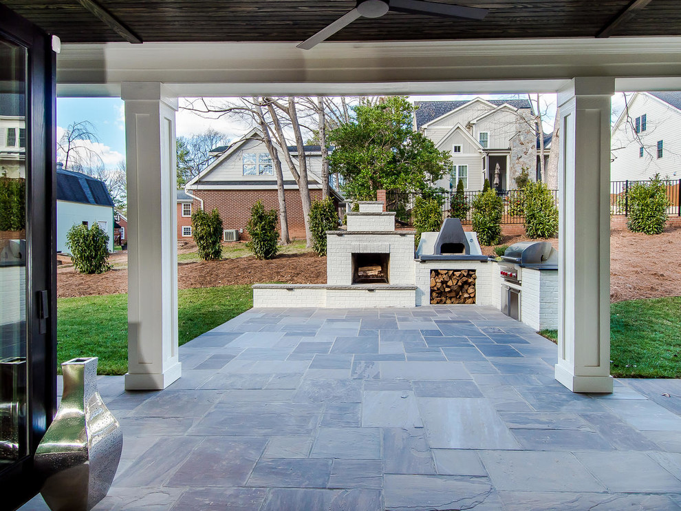 Photo of a medium sized classic back patio in Raleigh with natural stone paving and a roof extension.