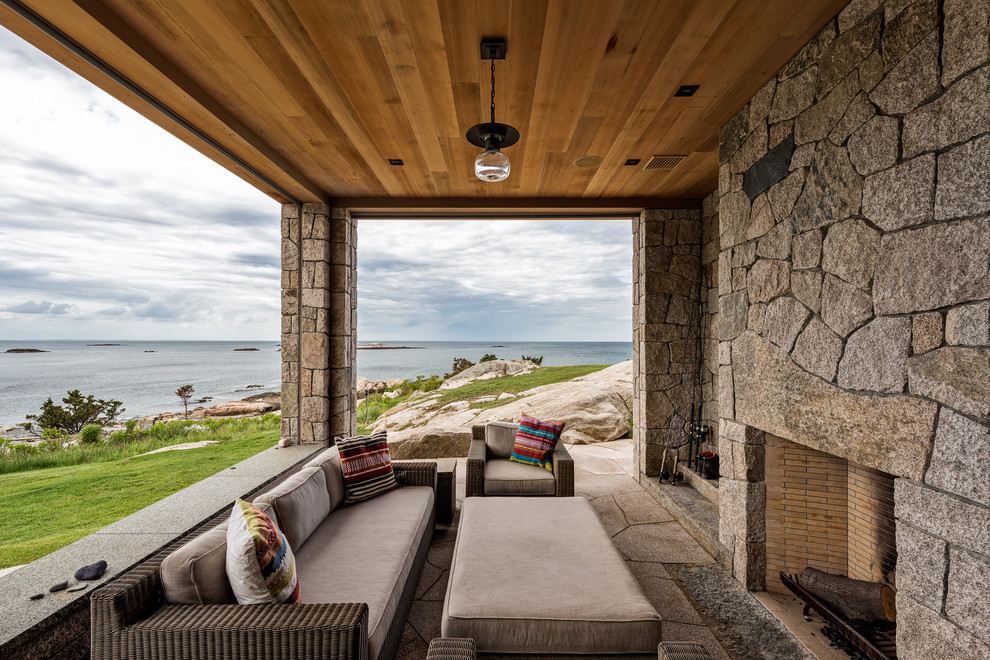 Inspiration for a beach style back patio in Boston with a fireplace, natural stone paving and a roof extension.