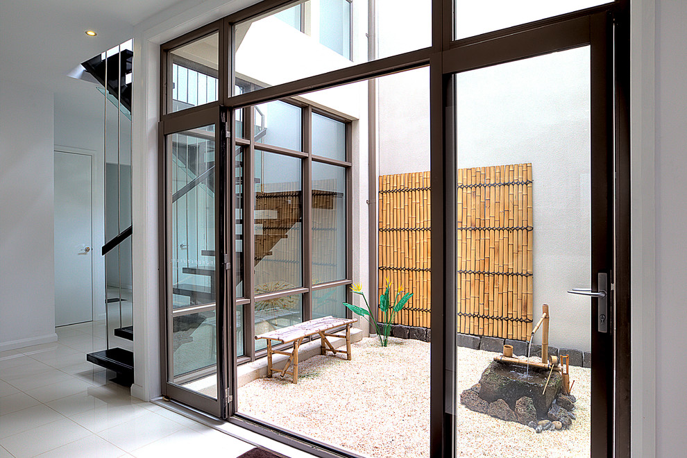 На фото: большой двор на внутреннем дворе в восточном стиле с покрытием из гравия, навесом и вертикальным садом с