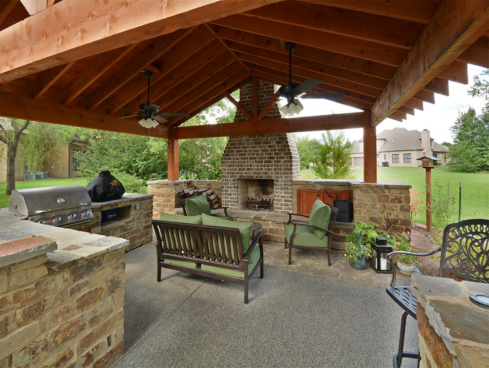 Idee per un grande patio o portico rustico dietro casa con un focolare, lastre di cemento e un gazebo o capanno