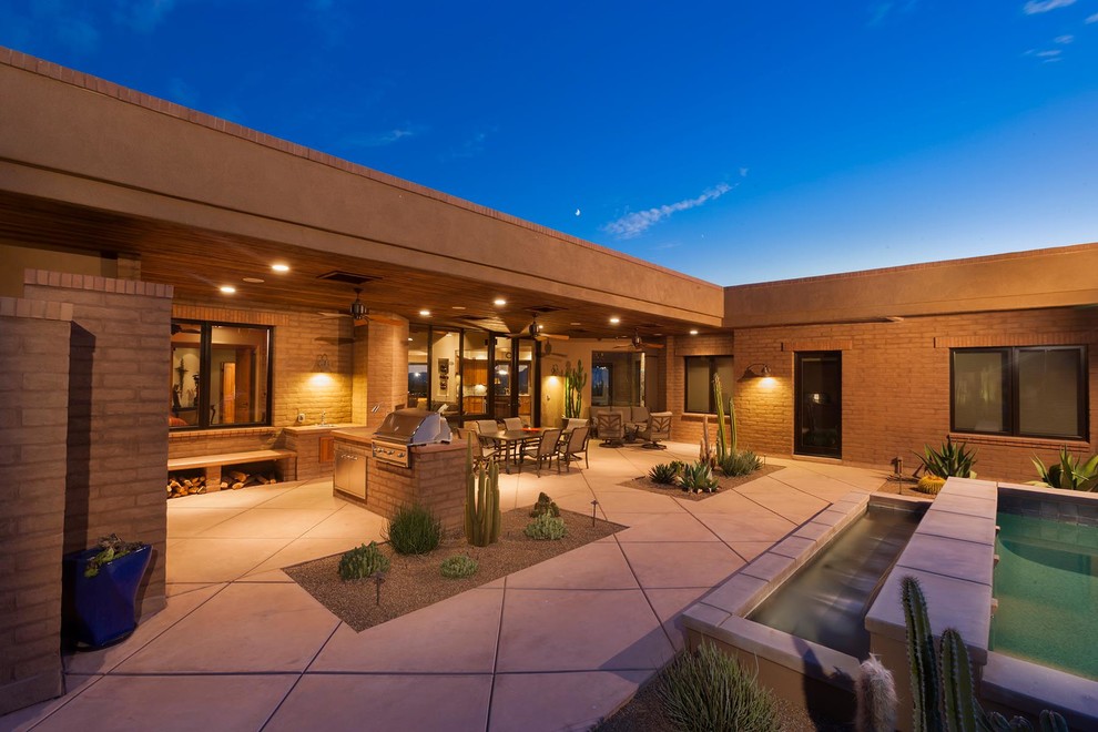 This is an example of an expansive traditional back patio in Phoenix with a roof extension, concrete paving and a bbq area.