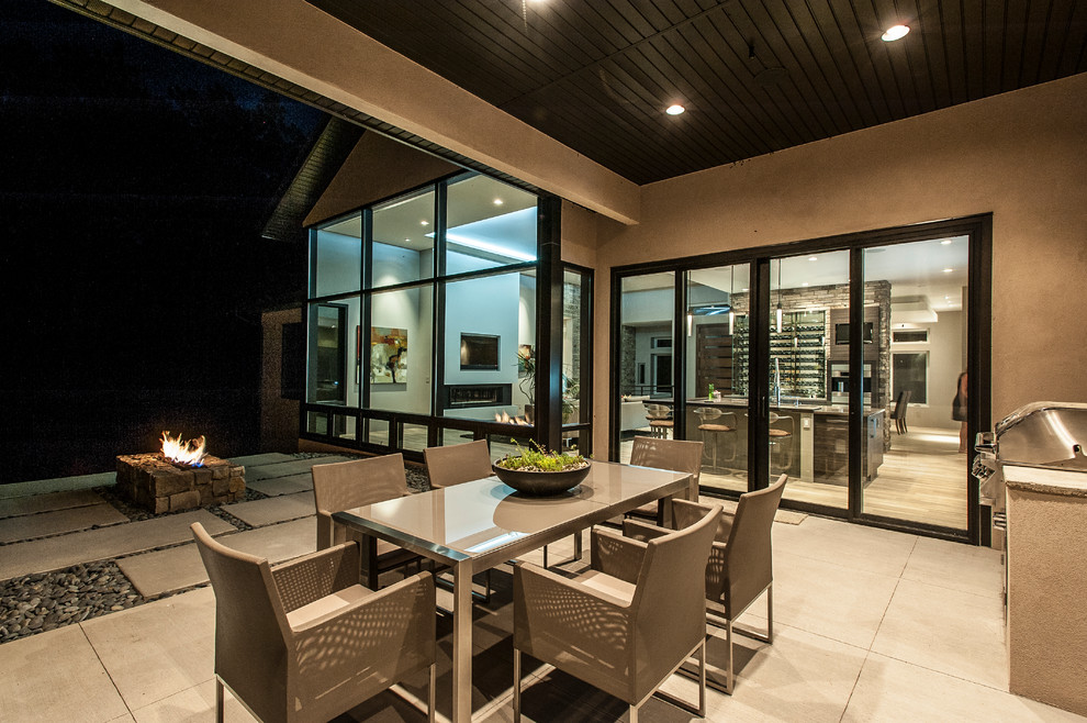 Inspiration pour une terrasse arrière design de taille moyenne avec un foyer extérieur, une dalle de béton et une extension de toiture.