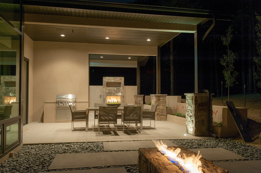 This is an example of a medium sized contemporary back patio in Denver with a fire feature, concrete slabs and a roof extension.