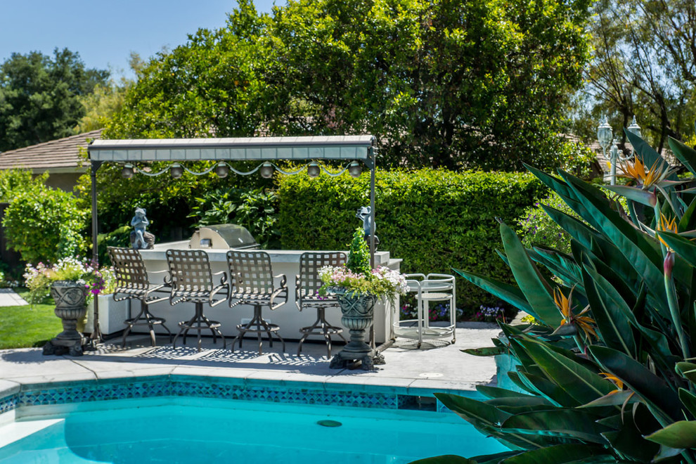 This is an example of a medium sized traditional back patio in San Francisco with an outdoor kitchen, concrete paving and an awning.