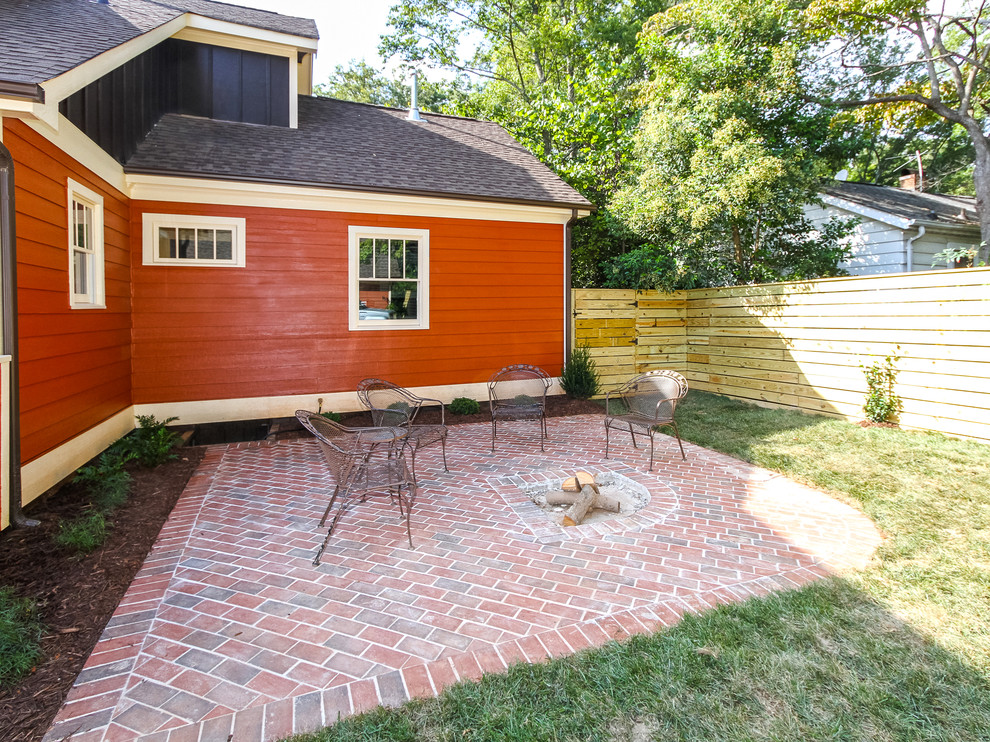 Imagen de patio de estilo americano de tamaño medio sin cubierta en patio trasero con brasero y adoquines de ladrillo