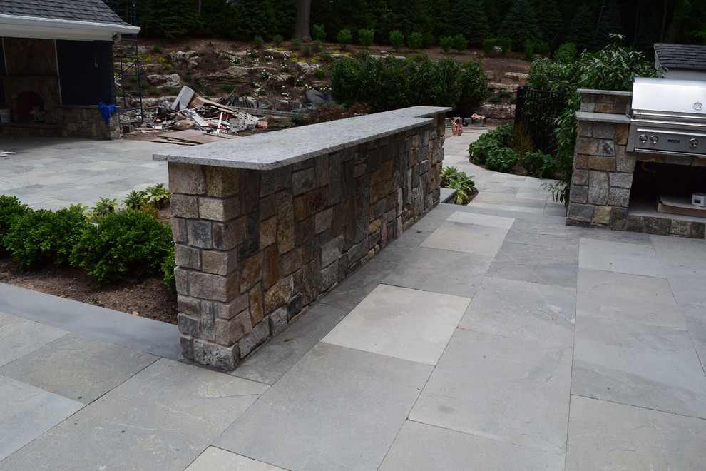 Large traditional patio in New York with an outdoor kitchen, natural stone paving and no cover.