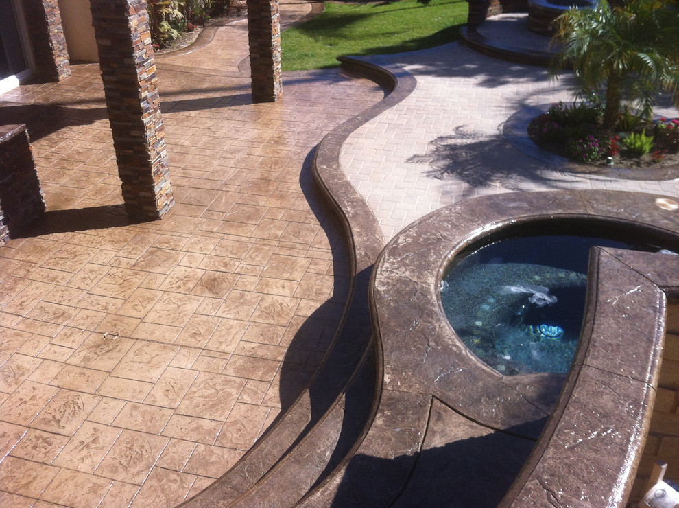 Esempio di un grande patio o portico tropicale dietro casa con pavimentazioni in pietra naturale e un tetto a sbalzo