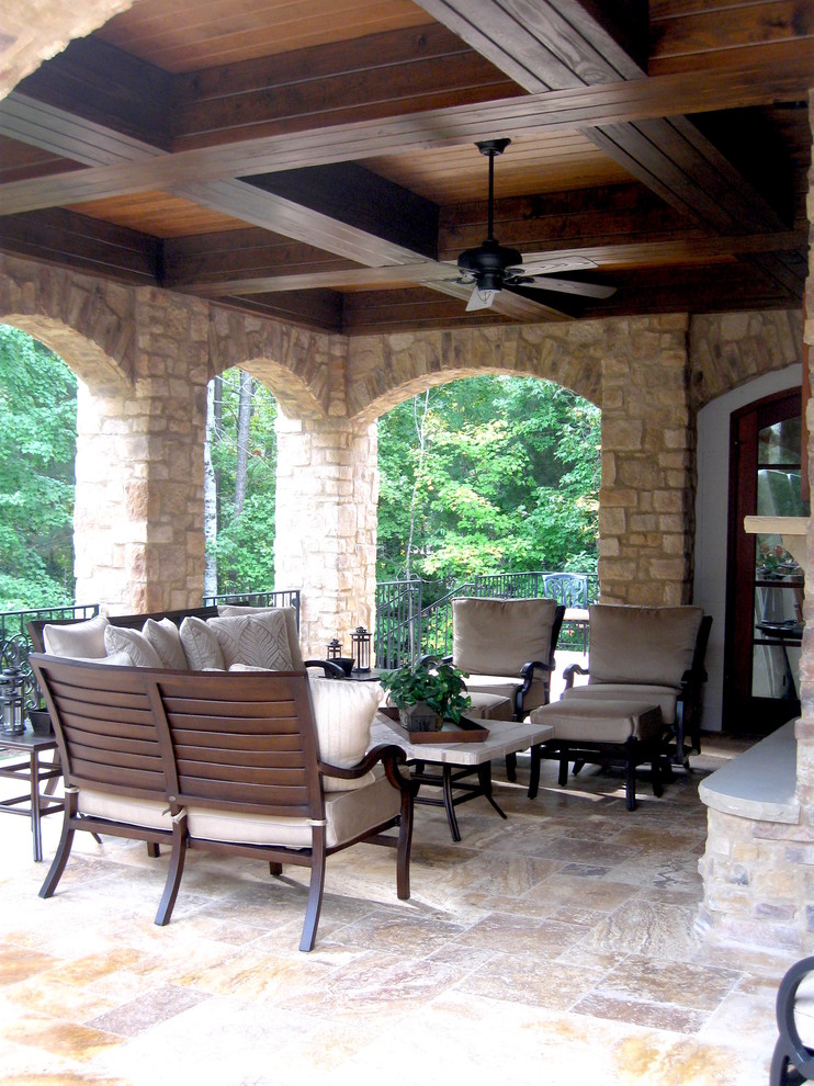 Example of a large classic backyard stone patio design in Raleigh with a roof extension