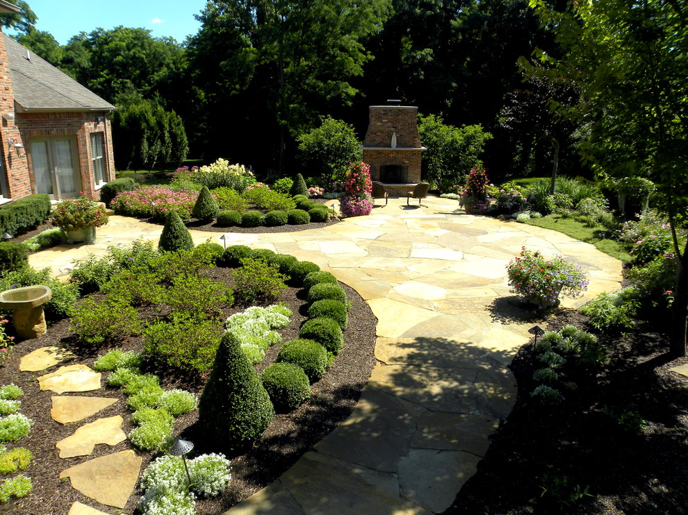 This is an example of an expansive world-inspired back patio in Chicago with a fire feature and natural stone paving.