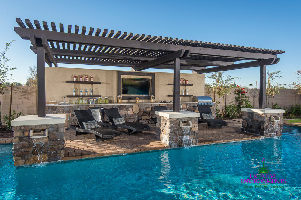 This is an example of an expansive modern back patio in Phoenix with an outdoor kitchen, brick paving and a pergola.
