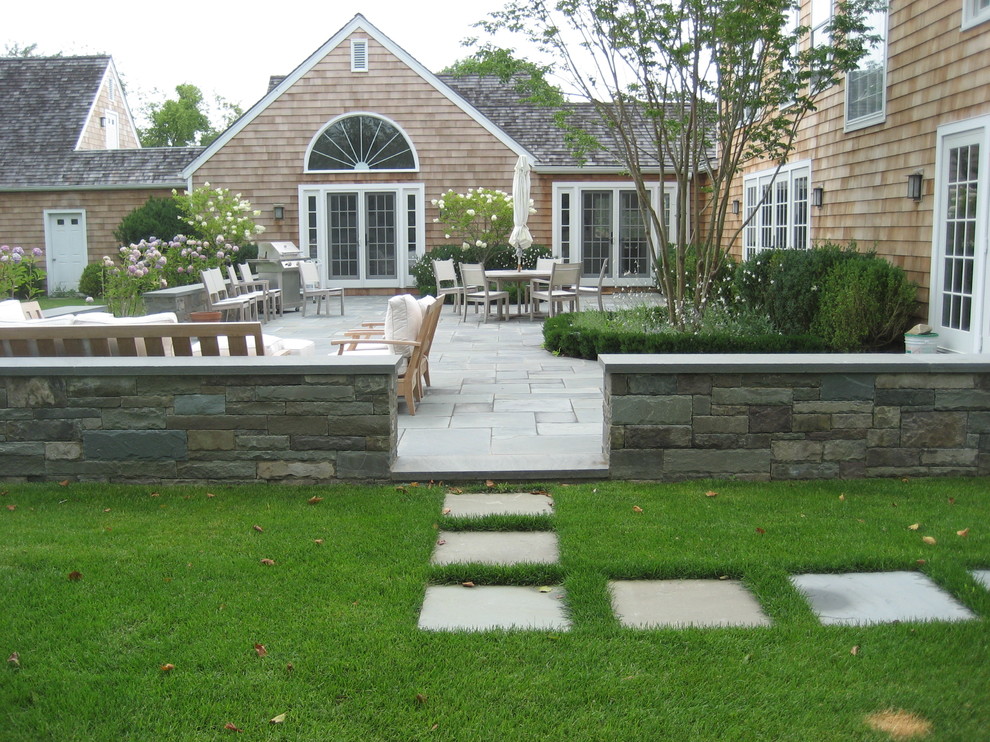 Cette photo montre une grande terrasse arrière chic avec des pavés en pierre naturelle et aucune couverture.